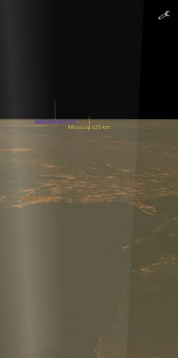 Phone screenshot: the night side of the Earth with distance-labeled towers on the horizon